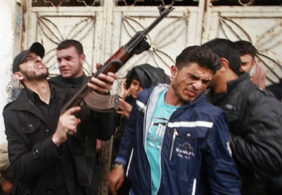 A Palestinian reacts as a gunman (L) fires a weapon in the air during the funeral of Islamic Jihad militant Mohammed Daher in Gaza City March 13, 2012. REUTERS/Suhaib Salem