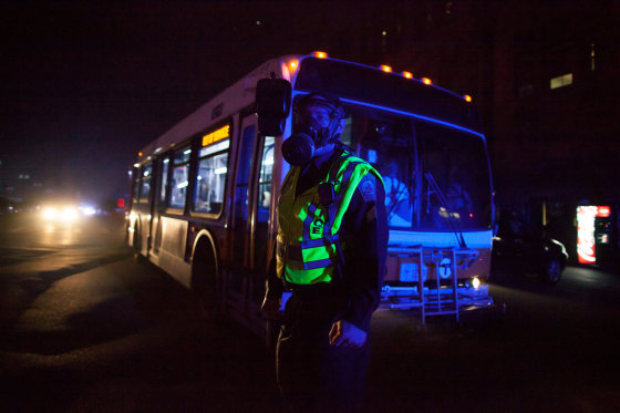 An police officer wears a protective mask as he helps load city buses after a transformer fire sent black smoke into streets and plunged parts of the city into darkness in the Back Bay section of downtown Boston March 13, 2012. A three alarm fire caused power problems as citizens were warned to avoid the area avoid breathing the smoke according to officials. REUTERS/Scott Eisen (UNITED STATES - Tags: ENERGY SOCIETY TPX IMAGES OF THE DAY)