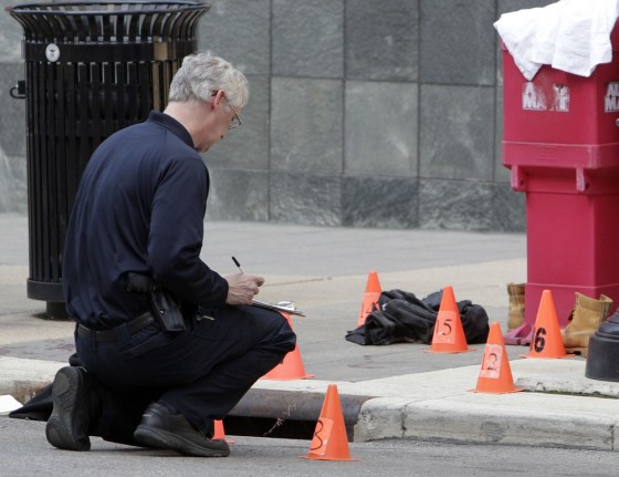 A member of the Columbus crime scene search unit investigates the scene where a man was shot by a Columbus police officer Wednesday, March 14, 2012, in Columbus, Ohio. The suspect was shot after stabbing four people in an attack that started inside Miami-Jacobs Career College. (AP Photo/Jay LaPrete)