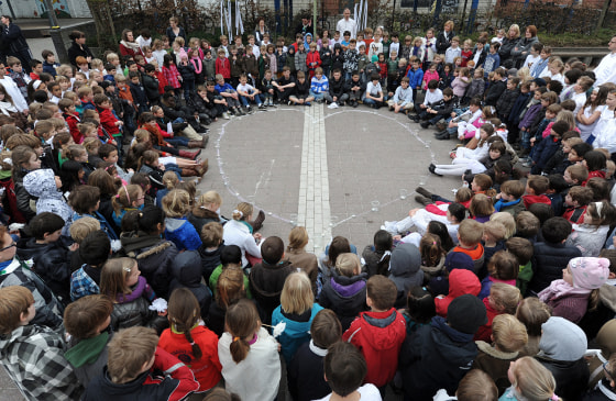 Children of primary school 'De Speling' in Lommel form a circle around a heart drawn with chalk on March 16, 2012 during a minute of silence at the 't Stekske primary school in Lommel for the victims of the March 13 bus crash near the town of Sierre in southern Switzerland. Twenty-eight people died in the accident, including 22 children from two schools of Lommel and Heverlee, returning to Belgium from a skiing holiday. Belgians observed a minute of silence and church bells tolled across the grieving nation on March 16 as the bodies of the victims were flown home. AFP PHOTO / BELGA - YORICK JANSENS (Photo credit should read YORICK JANSENS/AFP/Getty Images)