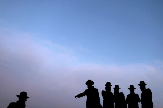 epa03161586 Ultra-Orthodox Jewish men silhouetted against the late afternoon sky as they gather at a mountain spring outside Jerusalem, 27 March 2012, in order to collect water for the making 'matza,' or unleavened bread prior to the start of Passover. EPA/ABIR SULTAN