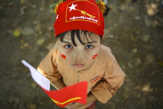 A child, with stickers of party flag of National League for Democracy (NLD) on his face, holds a party flag during the election campaign of NLD party in Yangon March 28, 2012. The parliamentary election is scheduled for Sunday in Myanmar. REUTERS/Staff (MYANMAR - Tags: POLITICS ELECTIONS SOCIETY)