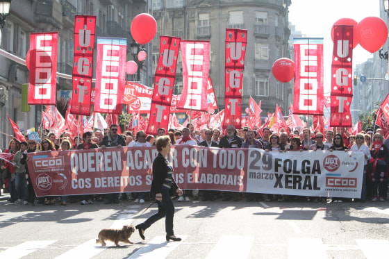 A woman walks past several thousand people taking part in a rally called by Spanish trade unions UGT and CCOO in Vigo, northwestern Spain, March 29, during the 24-hour general strike called in Spain to protest against the Government's labor reform.