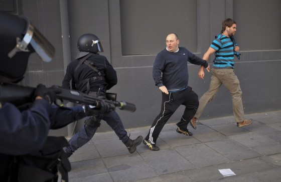Demonstrators run on the street as they try to flee riot police during a general strike to protest against the government's tough new labor reforms and cutbacks in Pamplona, northern Spain on March 29.
