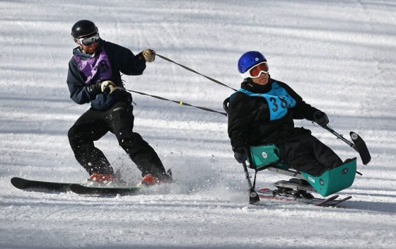 Disabled military veteran Manuel Siquig skis down the mountainside on a mono-ski with the help of an instructor on March 28, 2012 in Snowmass Village, Colorado.