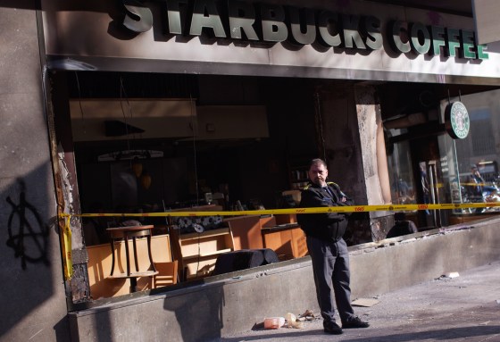 A security guard stands next to a Starbucks coffee shop stormed by demonstrators during clashes between police and protesters after a general strike in Barcelona, Spain, on March 30. The Spanish government prepared to approve on Friday a new austerity budget that hundreds of thousands protested against this week in sometimes violent demonstrations.