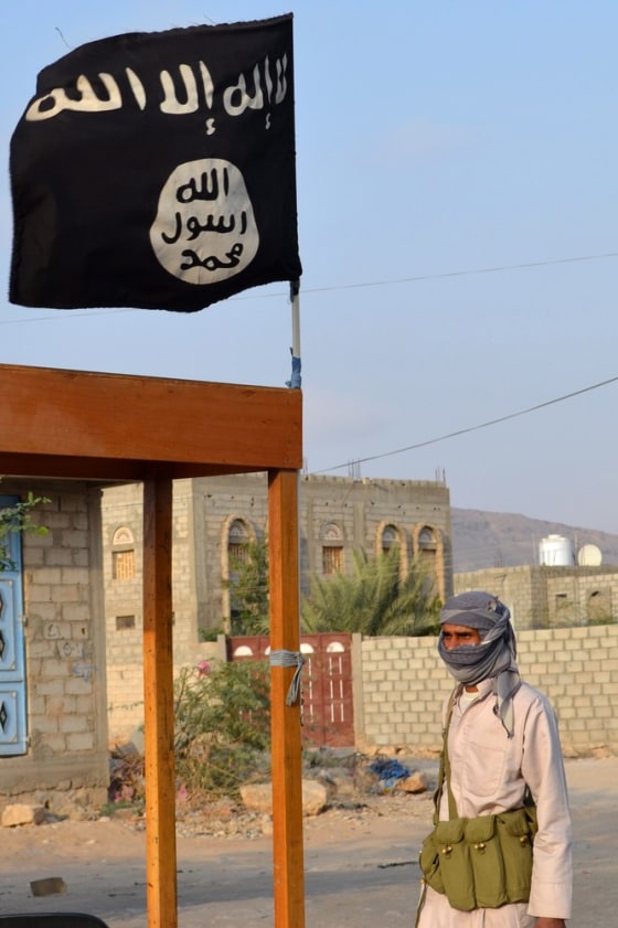 A member of militant group Ansar al-Sharia stands next to an al-Qaida flag at a checkpoint in the southern town of Azzan, Yemen, on March 31.