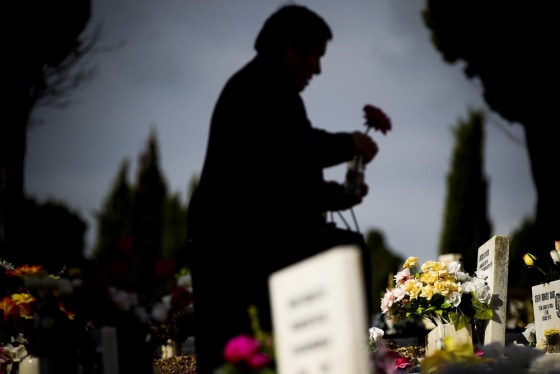 A woman places flowers on the grave of a relative at the cemetery of Benfica, on All Saints' Day, in Lisbon, Portugal on Nov. 1.