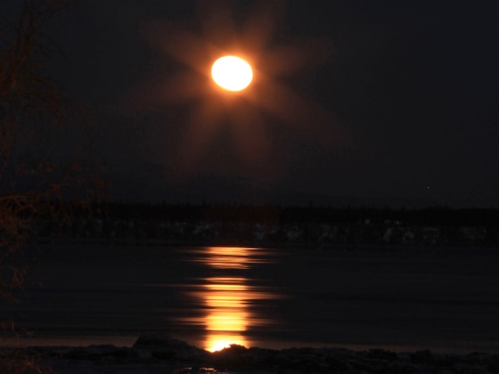 A nearly full moon sets over waters of Cook Inlet and a children's whale slippery slide just before sunrise on Tuesday, at Elderberry Park in downtown Anchorage, Alaska. Anchorage's next full moon is Wednesday.
