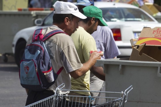 A man picks a piece of water melon from a trash container in Madrid Sunday Sept. 16, 2012. Eurozone unemployment hit 18.2 million people in August, the highest level since the euro's inception in 1999.