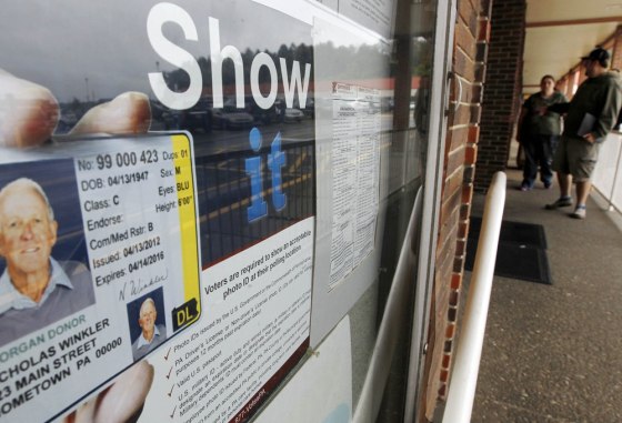 People pass the signs telling of the requirement for voters to show an acceptable photo ID to vote as they head into the the Penndot Drivers License Center in Butler, Pa.