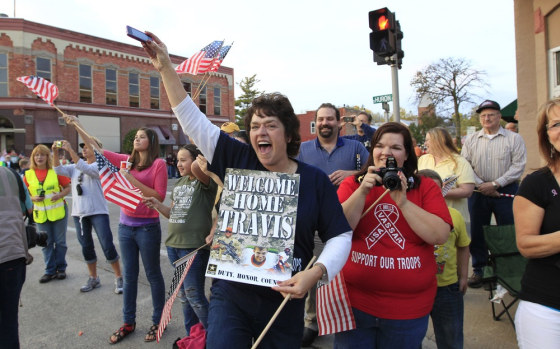 Julie Best, a friend of Travis Mills, cheers as he rides in the homecoming parade.