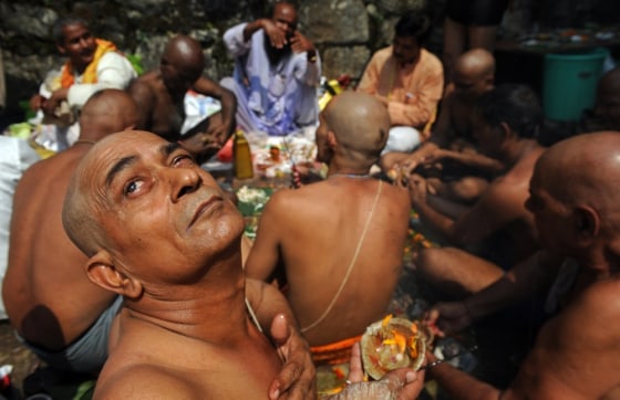 A Hindu devotee looks skyward as he and others perform