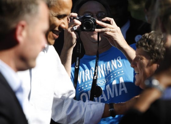 A supporter wearing a "Virginians for Obama" shirt takes a picture of U.S. President Barack Obama (L) as he greets supporters at his campaign office in Williamsburg, Virginia, October 14, 2012. REUTERS/Jonathan Ernst