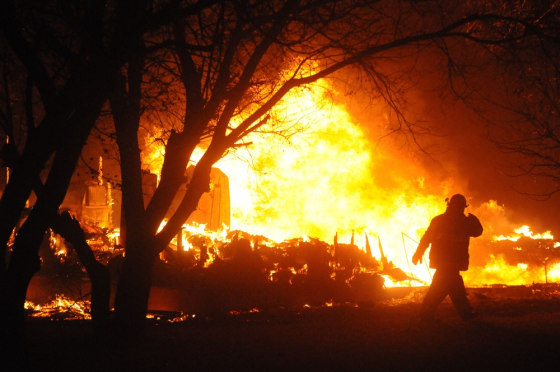 A firefighter examines the flames as a fire sweeps through Bucyrus, N.D., on Wednesday night.