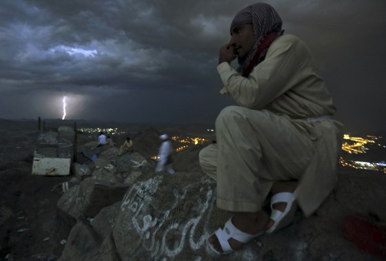 A Muslim pilgrim gestures as lightning strikes in the background at the top of Mount Noor where Muslims believe Prophet Mohammad received the first words of the Koran through Gabriel, during the annual haj pilgrimage in the holy city of Mecca, Oct. 21.