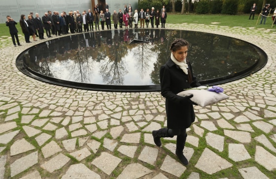Messina Weiss, 12 and great grand-daughter of Holocaust survivor Gertrud Rocher, carries a flower past the memorial to the Sinti and Roma in Berlin, Germany, on Wednesday.