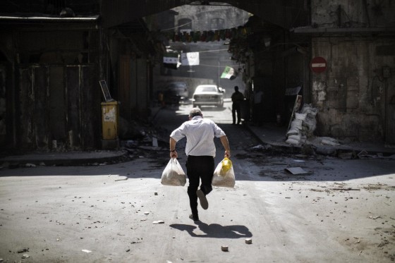 September 14: A man carrying grocery bags tries to dodge sniper fire as he runs through an alley near a checkpoint manned by the Free Syrian Army in the northern city of Aleppo. Syrian regime forces used fighter jets and helicopter gunships to pound the city and province of Aleppo, monitors said.