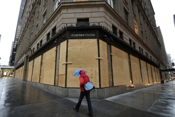 A woman walks past a boarded up Saks Fifth Avenue store in Manhattan on Oct. 29, 2012. The retailer's flagship New York store, along with five other stores in New Jersey and Connecticut, are set to reopen on Wednesday.
