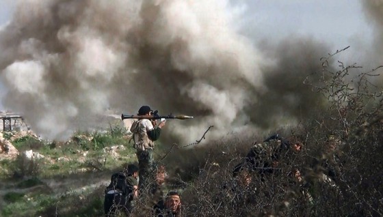 An image taken from video shows an opposition fighter holding a rocket-propelled grenade as his comrades take cover from an attack by regime forces Monday during a clash in Syria.