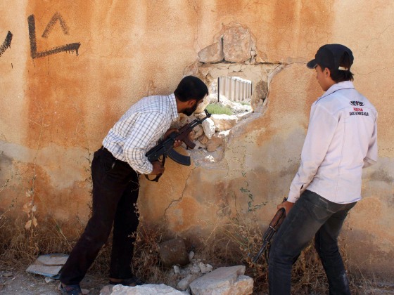 A Free Syrian Army fighter looks through a hole in a wall to determine the position of forces loyal to Syria's President Bashar al-Assad near Aleppo International Airport on Wednesday.