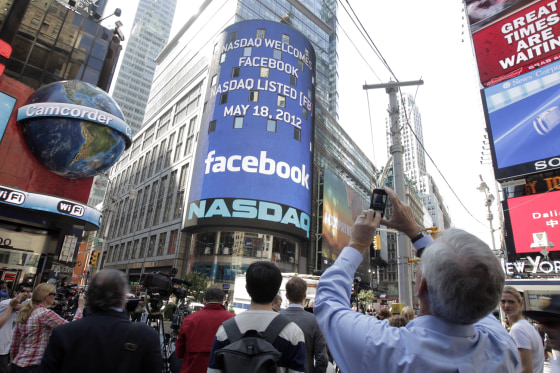 A man stops to photograph Nasdaq in Times Square as Facebook has its IPO, Friday, May 18, 2012, in New York. The social media company priced its IPO o...