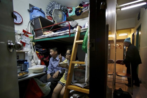 63-year-old Lee Tat-fong walks in a corridor while her two grandchildren -- Amy, 9, and Steven, 13 -- sit in their 50-square-foot room in Hong Kong on Jan. 25, 2013. Lee, like many poor residents, has applied for public housing but faces years of waiting. Nearly three-quarters of 500 low-income families questioned by Oxfam Hong Kong in a recent survey had been on the list for more than 4 years without being offered a flat.