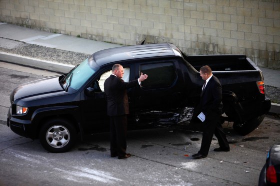 Police detectives investigate a shooting scene involving a black Honda pickup truck in Torrance, Calif. Police opened fire on the vehicle in a case of mistaken identity while searching for former Los Angeles police officer Christopher Dorner.