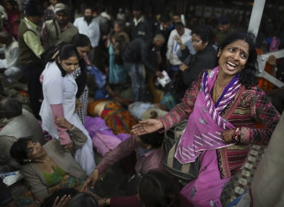 An Indian woman weeps as she and other family members mourn next to the body of a relative who was killed in a stampede on a railway platform at the main railway station in Allahabad, India, Sunday, Feb. 10, 2013. (AP Photo/Kevin Frayer)