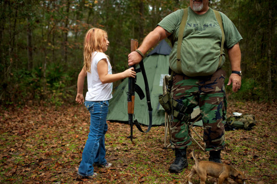 Brianna, 9, of the North Florida Survival Group hands an AK-47 rifle to Jim Foster, 57, the group's leader, before heading out to conduct enemy contact drills.