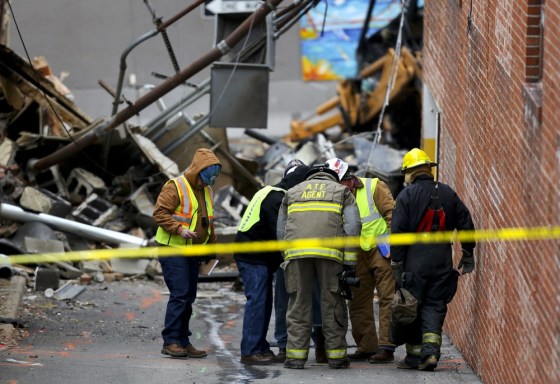 Investigators look down a hole in an alley near JJ's Restaurant after an explosion destroyed the establishment Tuesday, Feb. 19, in Kansas City, Mo.