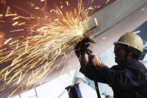 A laborer polishes the bottom of a cargo ship at a shipyard in Qingdao, Shandong province July 1, 2013.