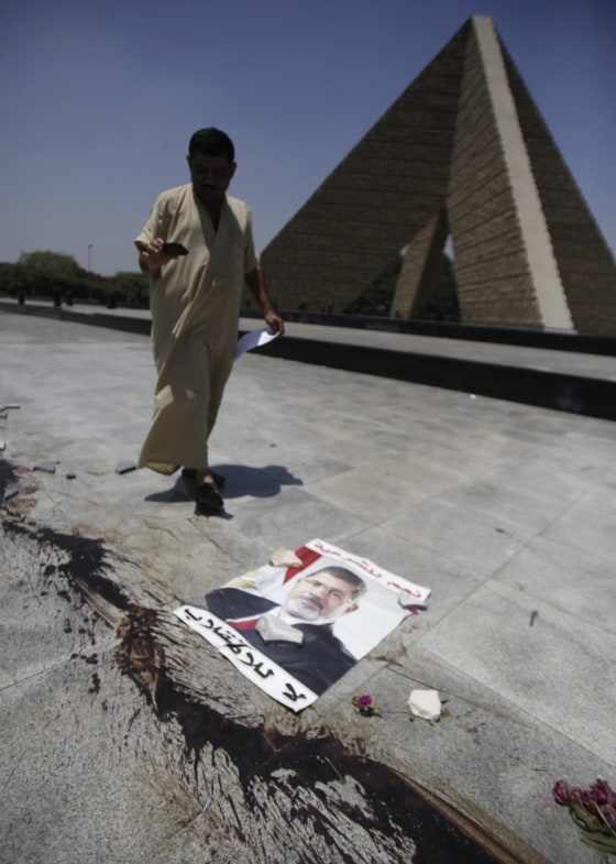A member of the Muslim Brotherhood and supporter of deposed Egyptian President Mohamed Mursi walks near a Poster of Mursi and bloodstains from protesters who were killed during late night clashes at the Tomb of the Unknown Soldier, near Rabaa Adawiya Square, Saturday.