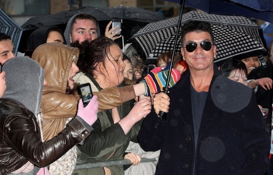 Reality-TV impresario Simon Cowell poses for photos with fans as