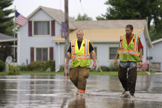New Hartford firefighters Clint Olmstead, left, and Jon LeBahn walk through floodwaters on Tuesday in New Hartford, Iowa. Hundreds of residents obeyed an order to evacuate their homes in this northeast Iowa town before floodwaters from a rising creek could strand them.