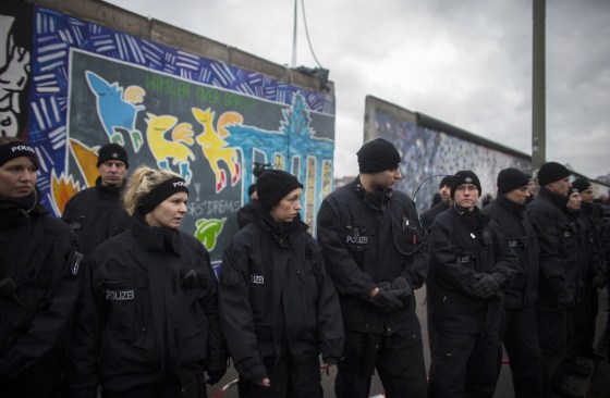 Police keep watch as workers remove a piece of the former Berlin Wall, now known as East Side Gallery, in Berlin on March 1, 2013.