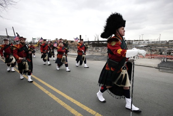 The Staten Island Pipes and Drum band marches in the Queens County St. Patrick's Day Parade in the Rockaway section of New York on Saturday. The oceanside community was devastated by flooding and fire during Superstorm Sandy. Behind them is rubble left over from a fire that burned a number of stores in Rockaway Park.
