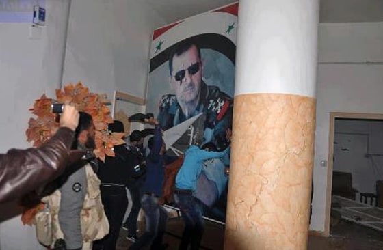 Citizen journalism image provided by Coordination Committee in Kafr Susa which has been authenticated based on its contents and other AP reporting, shows people tearing down a huge poster of President Bashar Assad and hitting it with their shoes, in Raqqa, Syria, Monday, March. 4, 2013. The activists said the picture was taken inside the Air Force Intelligence headquarters in Raqqa.