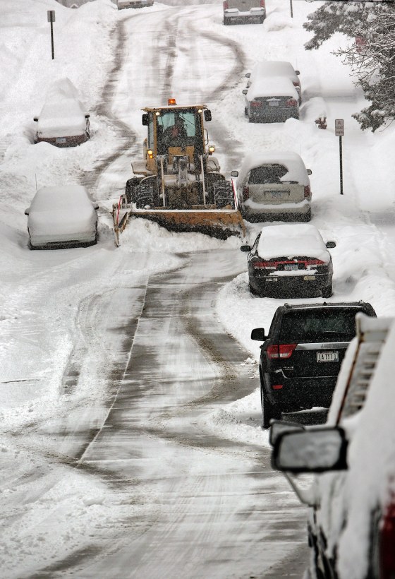 A snow plow slowly navigates around parked cars along West 3rd Street in Dubuque, Iowa during a snow storm Tuesday March 5. Forecasters say more snow is on the way to snarl travel and disrupt people's daily routines.