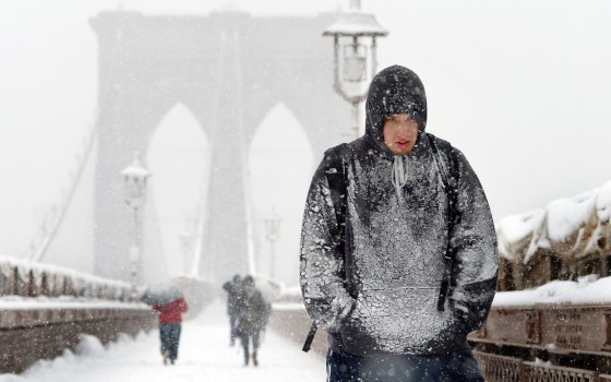 A man covered in snow walks across the Brooklyn Bridge during a snow storm in New York, on March 8.