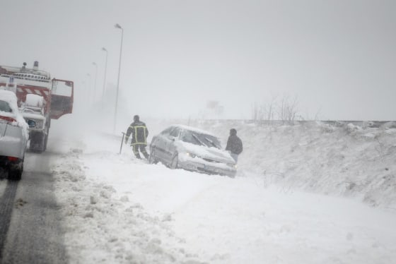 Firefighters rescue a driver who slid from a roadside during a heavy snowstorm in Caen, northwestern France, on March 12, 2013.