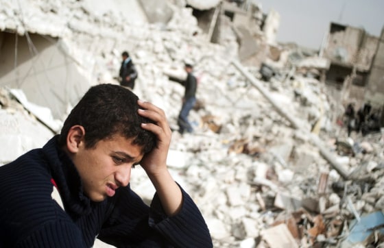 A Syrian teenager is among those surrounded by rubble after a missile attack in Aleppo on Feb. 23. The charity Save the Children has issued a report saying young people are facing horrific abuses during the war, which has claimed more than 70,000 lives so far.