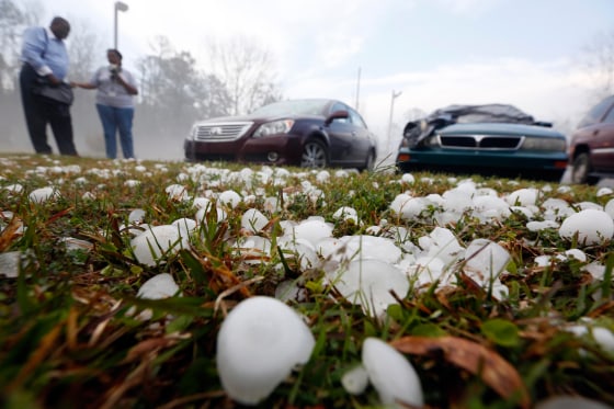 Golf ball-sized hail litter the ground by Andrew Stamps and his wife Valorie as they prepare to cover their shattered rear window of her 2009 Toyota Avalon in Pearl, Miss., Monday, March 18, 2013, following a hailstorm that hit communities throughout central Mississippi.
