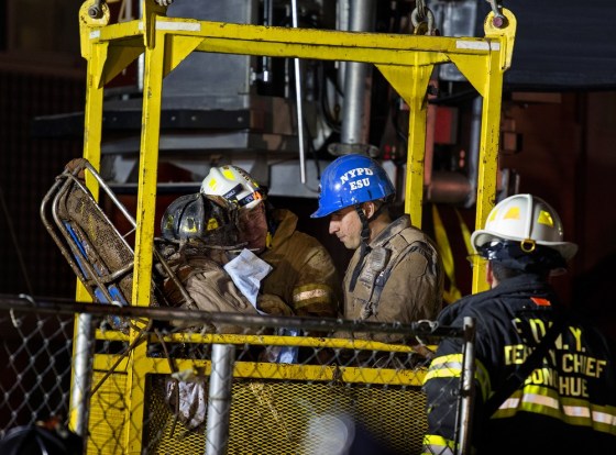 A worker, with black fire helmet at left, is rescued from an MTA subway construction project in New York early Wednesday.