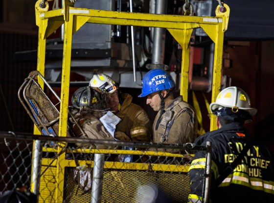A worker, left wearing a black fire helmet, is rescued from an MTA subway construction project in New York early on March 20, after being trapped up to his chest in debris for several hours. Fire officials say he is awake and conscious and is being evaluated at a local hospital.