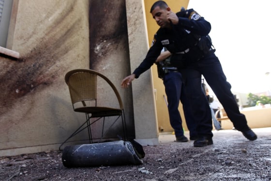 Israeli police officers stand near the remains of a rocket fired by Palestinian militants after it landed in the town of Sderot on Thursday.
