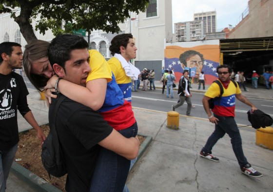 An opposition student protester carries a fellow protester after police launched tear gas during their march toward the electoral commission in downtown Caracas on Thursday.