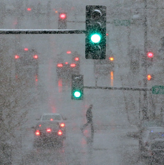 A pedestrian is shrouded in heavy snow as he crosses a downtown street on Saturday, March 23, in Kansas City, Mo.