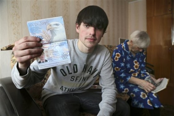 Alexander Abnosov shows his American passport to journalists in the Volga river city of Cheboksary, Russia, on March 20. His 72 -years old grandmother is in the background.