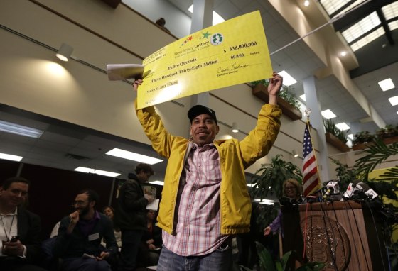 Pedro Quezada, the winner of the Powerball jackpot, holds up a promotional check during a news conference at the New Jersey Lottery headquarters.